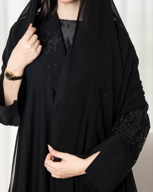 امرأة سعودية بعباية سوداء مطرزة وساعة ذهبية