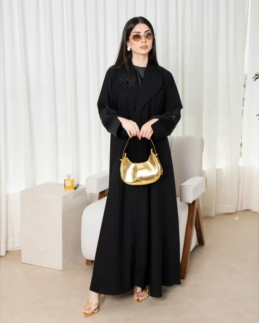 امرأة سعودية بعباءة سوداء عصرية وحقيبة يد ذهبية