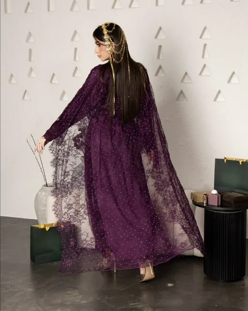امرأة سعودية بعباية أرجوانية ومجوهرات ذهبية للرأس