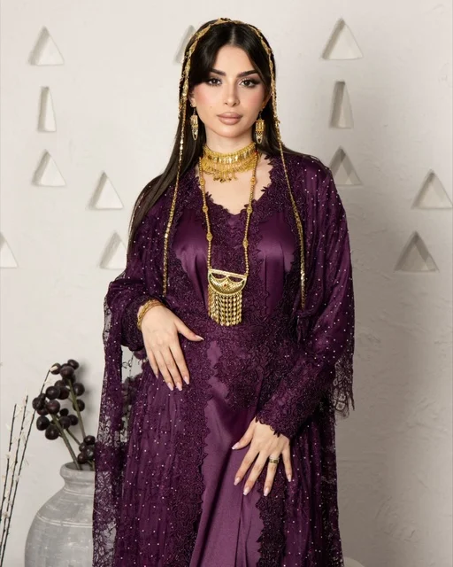 امرأة سعودية بزي بنفسجي أنيق ومجوهرات ذهبية تقليدية