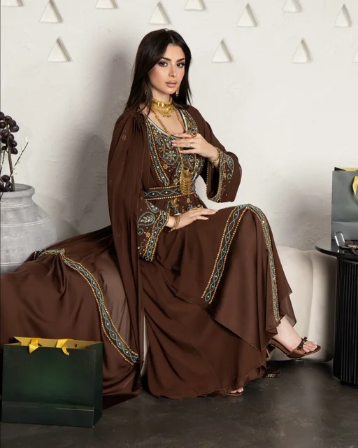 امرأة سعودية بفستان بني مطرز وأزياء خليجية
