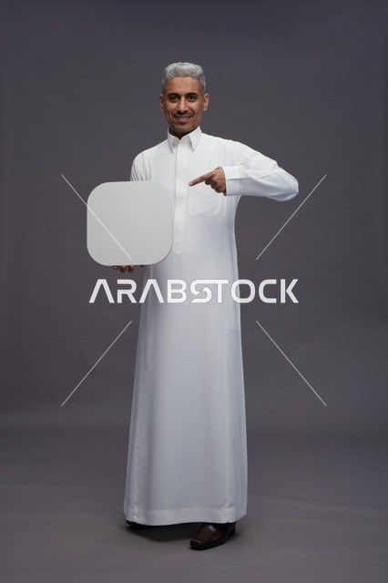 رجل سعودي بالثوب يشير إلى لوحة بيضاء فارغة