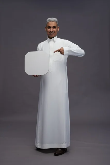 رجل سعودي بالثوب يشير إلى لوحة بيضاء فارغة