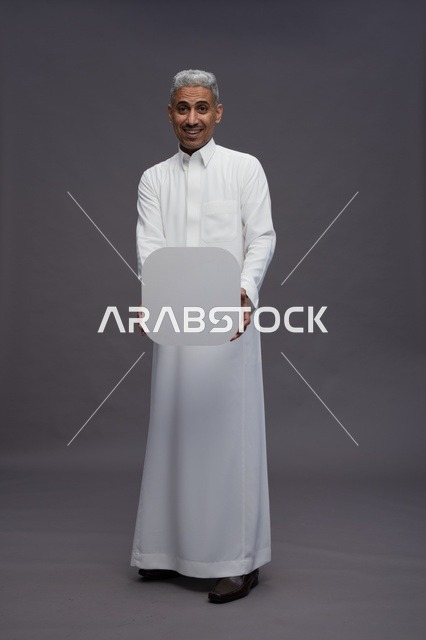 رجل سعودي بالثوب الأبيض يمسك لوحة بيضاء فارغة