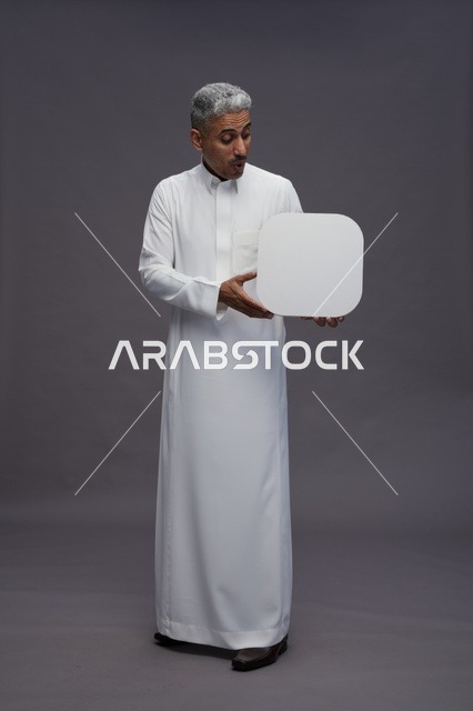 رجل سعودي بالثوب الأبيض يمسك لوحة إعلانية فارغة
