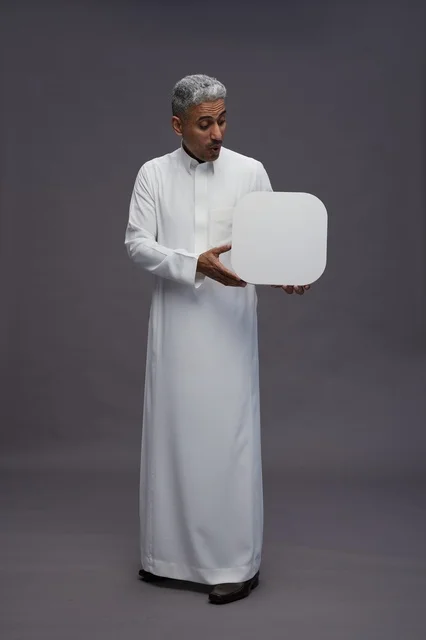 رجل سعودي بالثوب الأبيض يمسك لوحة إعلانية فارغة