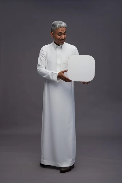 رجل سعودي يحمل لوحة بيضاء فارغة في الاستوديو