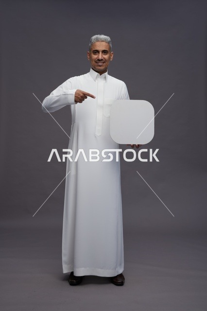 Saudi Man in Thobe Pointing at Blank Sign Studio Shot