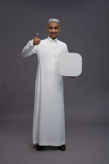 رجل سعودي بالثوب يحمل لوحة فارغة وإشارة إعجاب