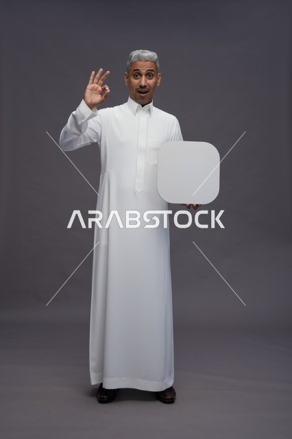 رجل سعودي بالثوب يحمل لوحة بيضاء فارغة
