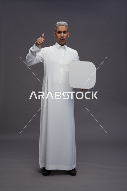 رجل سعودي بالثوب يحمل لوحة فارغة وعلامة إعجاب