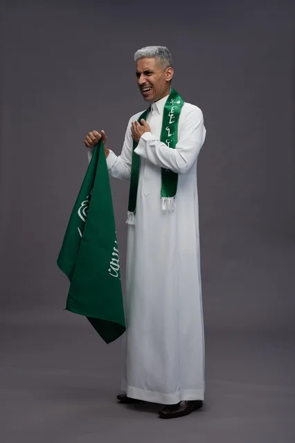 رجل سعودي بالثوب يحمل العلم الوطني في الاستوديو