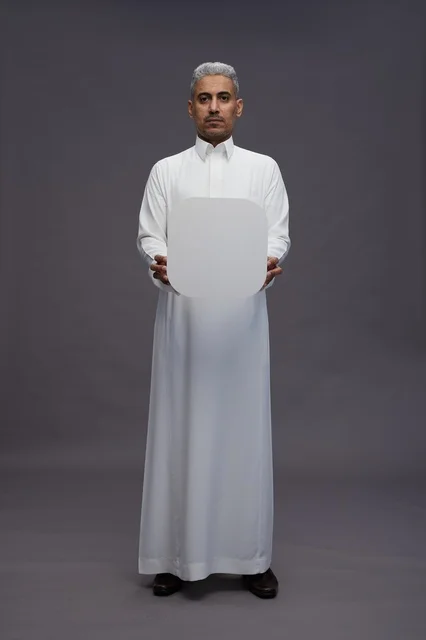 رجل سعودي بالثوب يحمل لوحة بيضاء فارغة