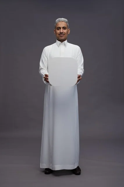 رجل سعودي بالثوب الأبيض يمسك لوحة بيضاء فارغة