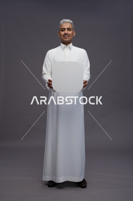 رجل سعودي يحمل لوحة بيضاء فارغة في الاستوديو