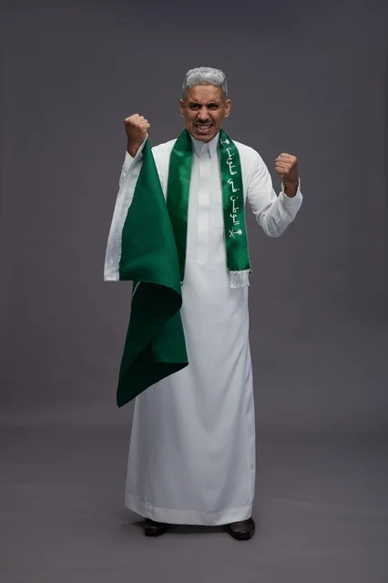 رجل سعودي مسن يحتفل بالعلم على خلفية رمادية