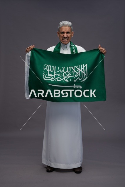 رجل سعودي يحمل العلم الوطني في استوديو