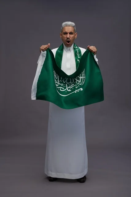 رجل سعودي يحمل العلم الوطني ويحتفل بخلفية رمادية