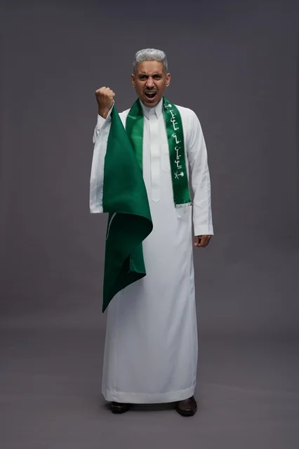 Saudi Man Cheering with National Flag in White Thobe