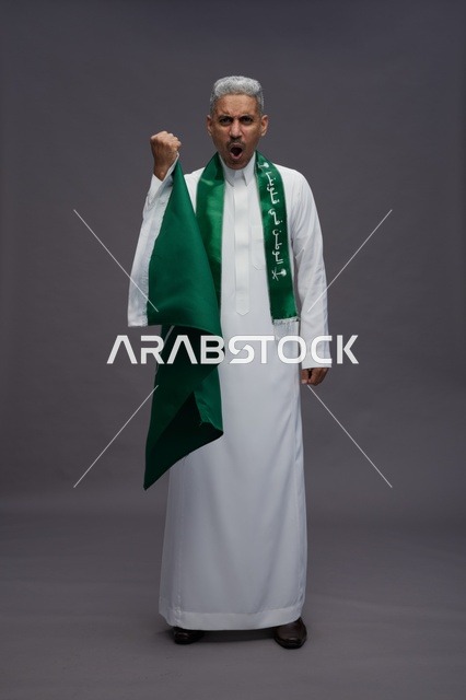 Saudi Man Celebrating National Day with Flag in Studio