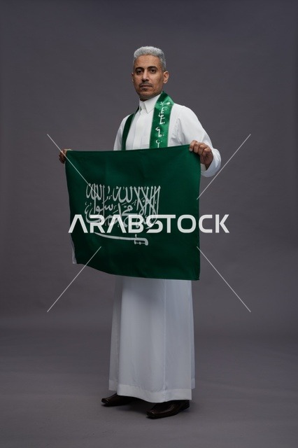 رجل سعودي يحمل العلم الوطني في استوديو