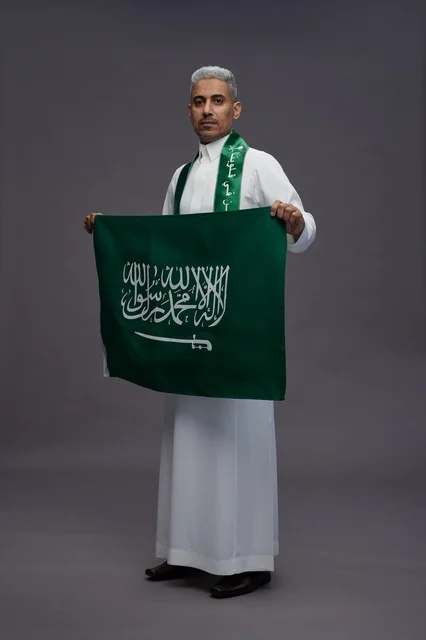 رجل سعودي يحمل العلم الوطني في استوديو