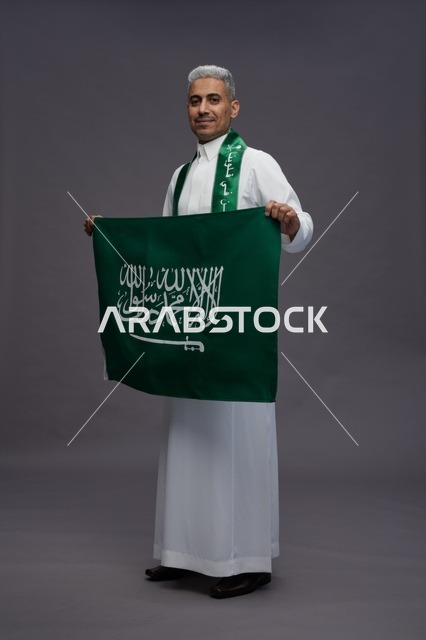 رجل سعودي يحمل العلم الوطني في الاستوديو