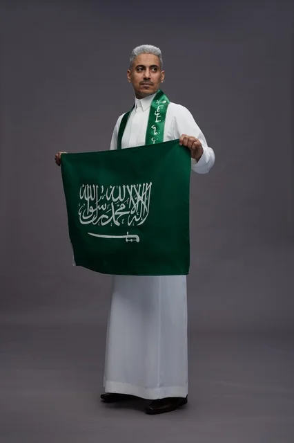 رجل سعودي بالثوب التقليدي يحمل العلم الوطني