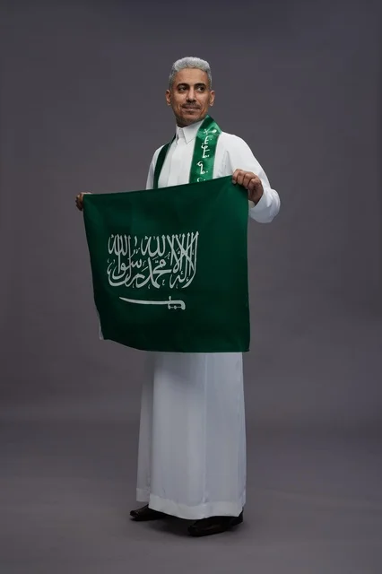 رجل سعودي يحمل علم السعودية في الاستوديو
