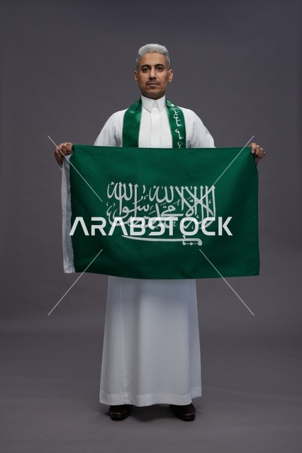 رجل سعودي يحمل العلم الوطني في استوديو التصوير