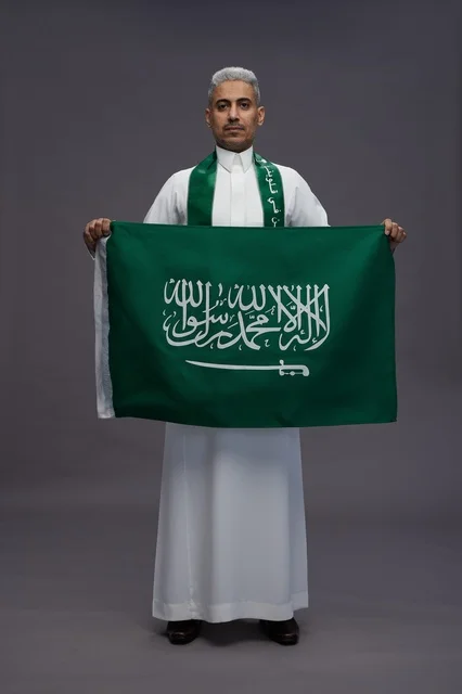 رجل سعودي يحمل العلم الوطني في استوديو التصوير