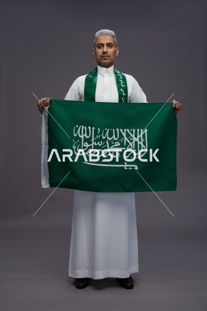 رجل سعودي يمسك بالعلم الوطني السعودي