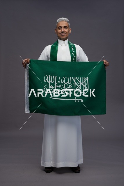 رجل سعودي يحمل علم المملكة العربية السعودية