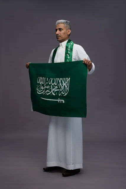 رجل سعودي بالثوب التقليدي يحمل علم المملكة