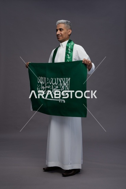 رجل سعودي يحمل العلم الوطني في استوديو تصوير