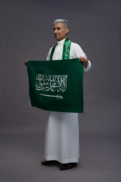 رجل سعودي يحمل العلم الوطني في استوديو تصوير