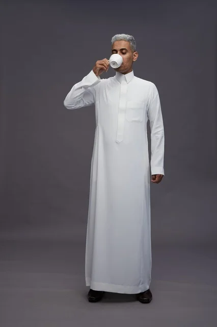 رجل سعودي بالثوب الأبيض التقليدي يشرب القهوة