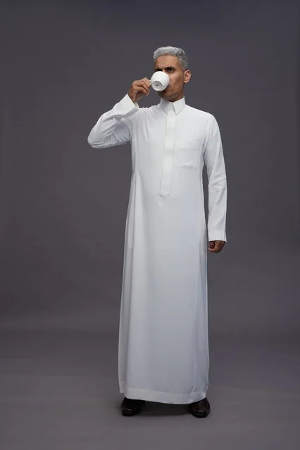 رجل سعودي بالثوب الأبيض يشرب القهوة في الاستوديو