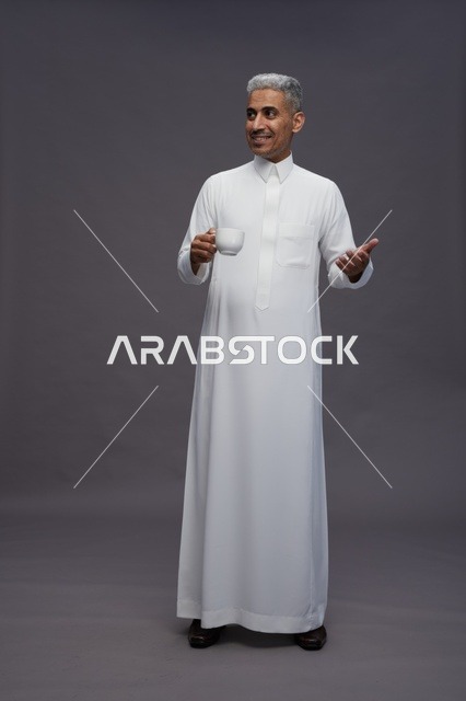 رجل سعودي بالثوب الأبيض يحمل فنجان قهوة
