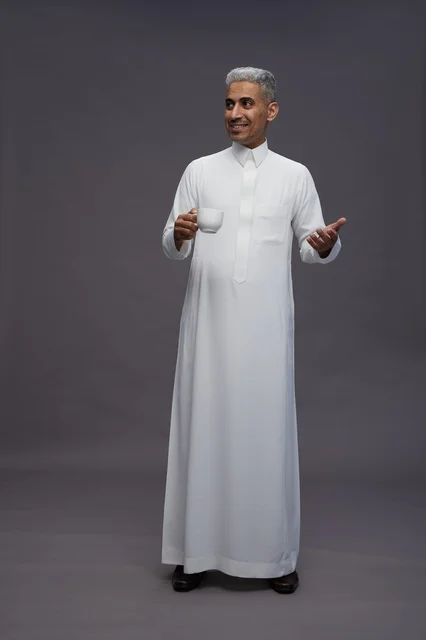 رجل سعودي بالثوب الأبيض يحمل فنجان قهوة