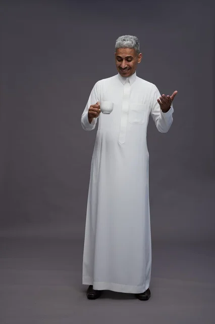 رجل سعودي بالثوب التقليدي يحمل فنجان قهوة
