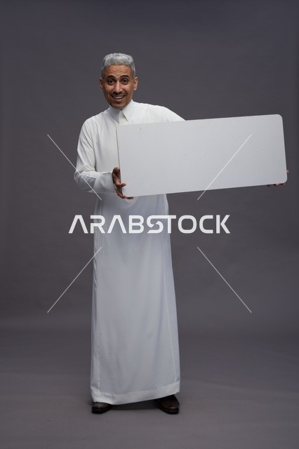 رجل سعودي يحمل لوحة بيضاء فارغة في الاستوديو