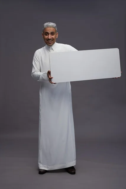 رجل سعودي يحمل لوحة بيضاء فارغة في الاستوديو
