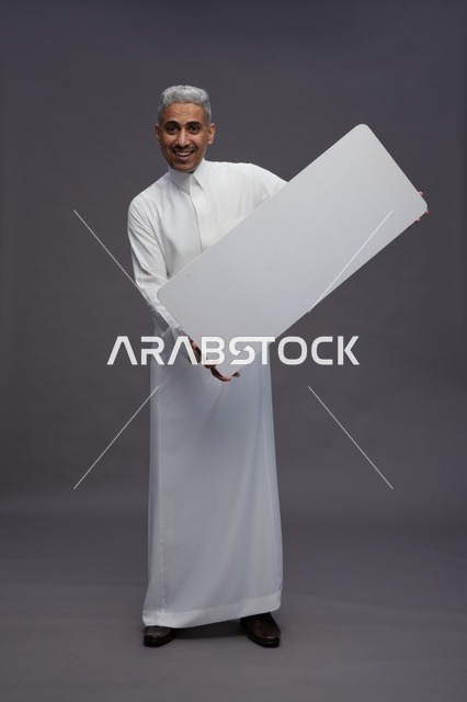 رجل سعودي يحمل لوحة بيضاء فارغة في الاستوديو