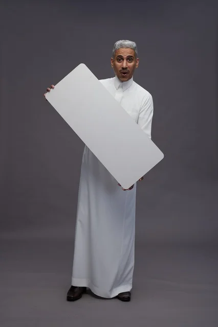 رجل سعودي يحمل لوحة بيضاء فارغة خلفية رمادية
