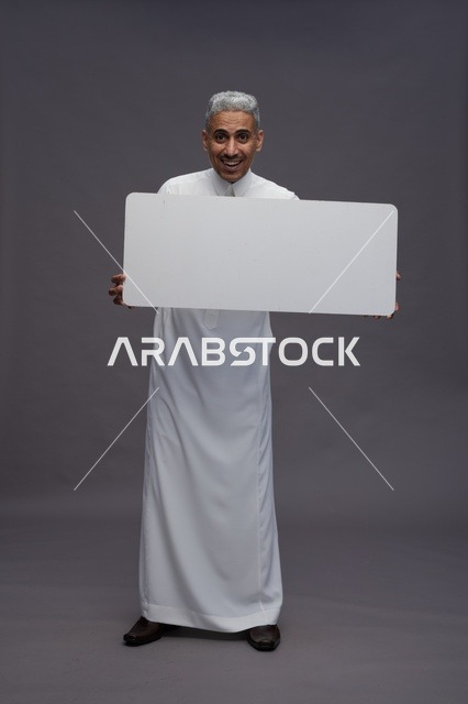رجل سعودي يمسك لوحة بيضاء فارغة في الاستوديو