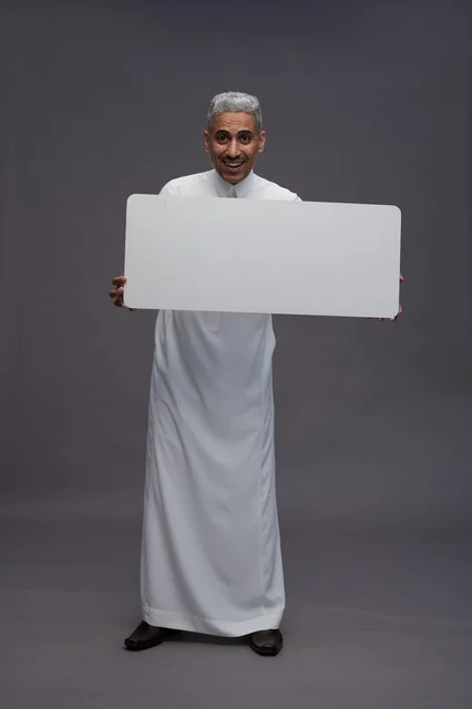 رجل سعودي يمسك لوحة بيضاء فارغة في الاستوديو