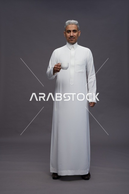 رجل سعودي بالثوب الأبيض يحمل فنجان قهوة