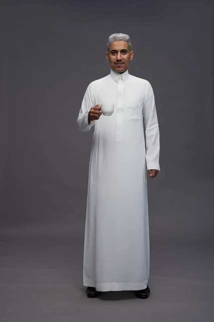 رجل سعودي بالثوب الأبيض يحمل فنجان قهوة