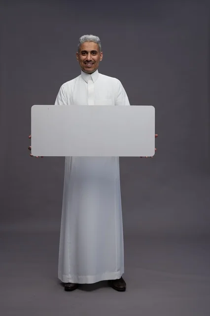رجل سعودي يمسك لوحة بيضاء فارغة في الاستوديو
